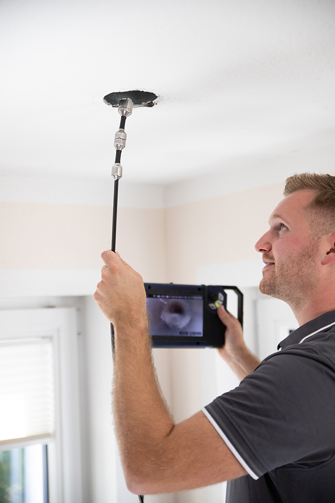 Mann inspiziert Rohr mit Kamera